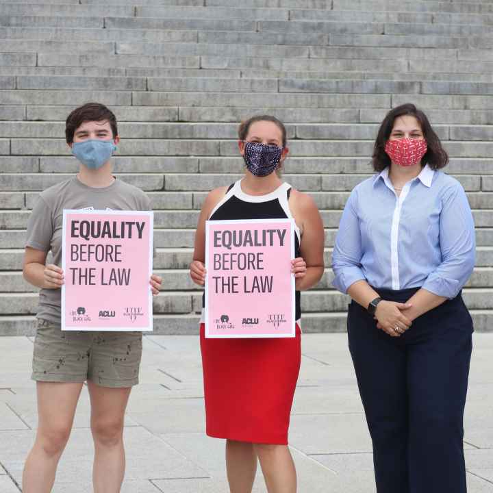 Four ACLU staff members stand outside the Nebraska State Capitol, three of whom are holding signs reading "Equality Before the Law."